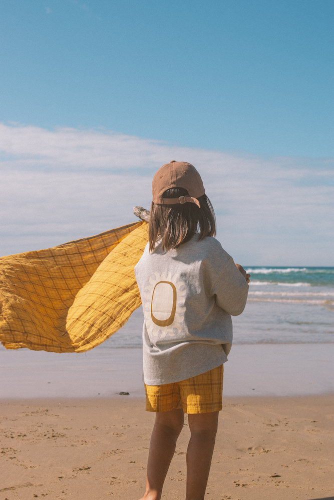 Child wearing a grey shirt and yellow shorts at the beach