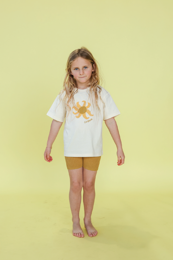 Young girl wearing a white t-shirt with a sun design on a yellow background