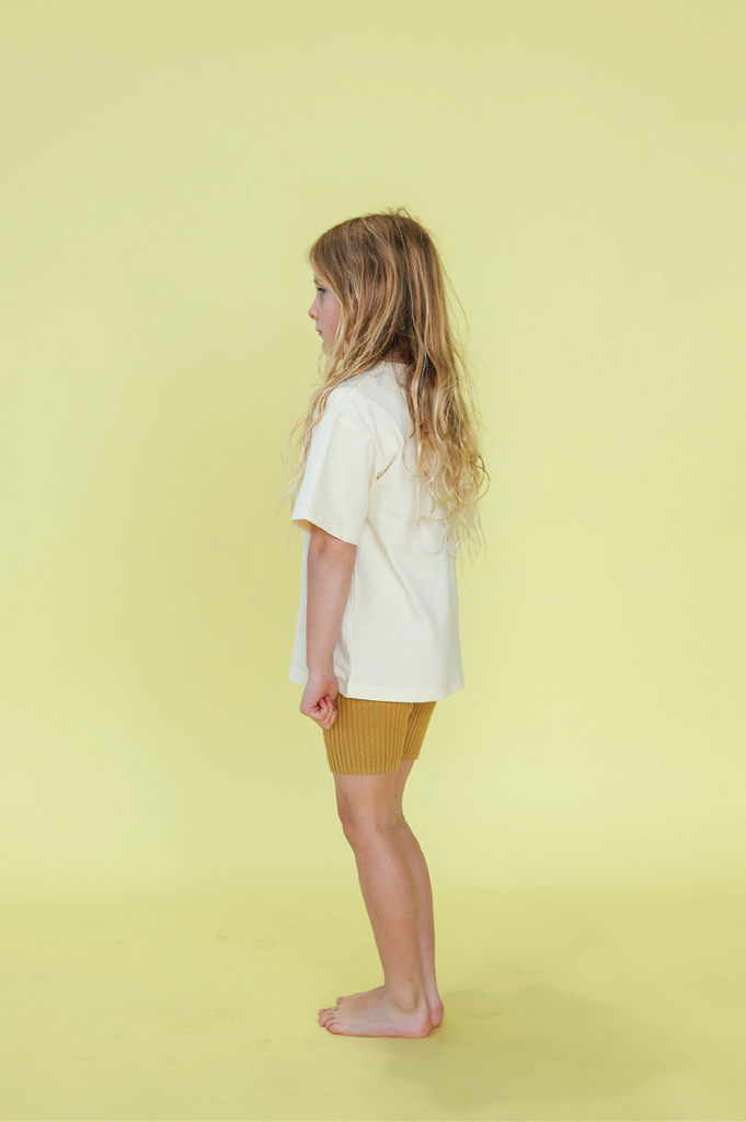 Young girl wearing a white t-shirt with a sun design on a yellow background