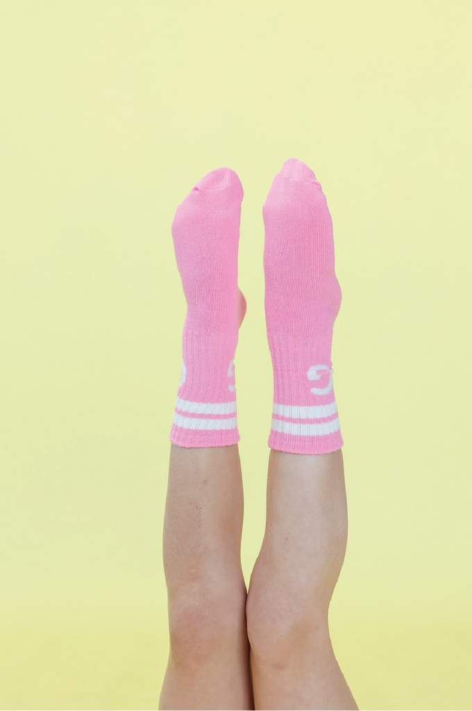 Pink crew socks with white stripes on a yellow background