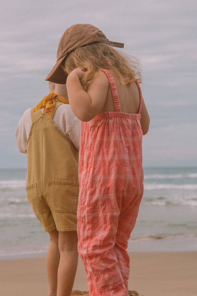 Young girl wearing a pink checkered overalls at the beach