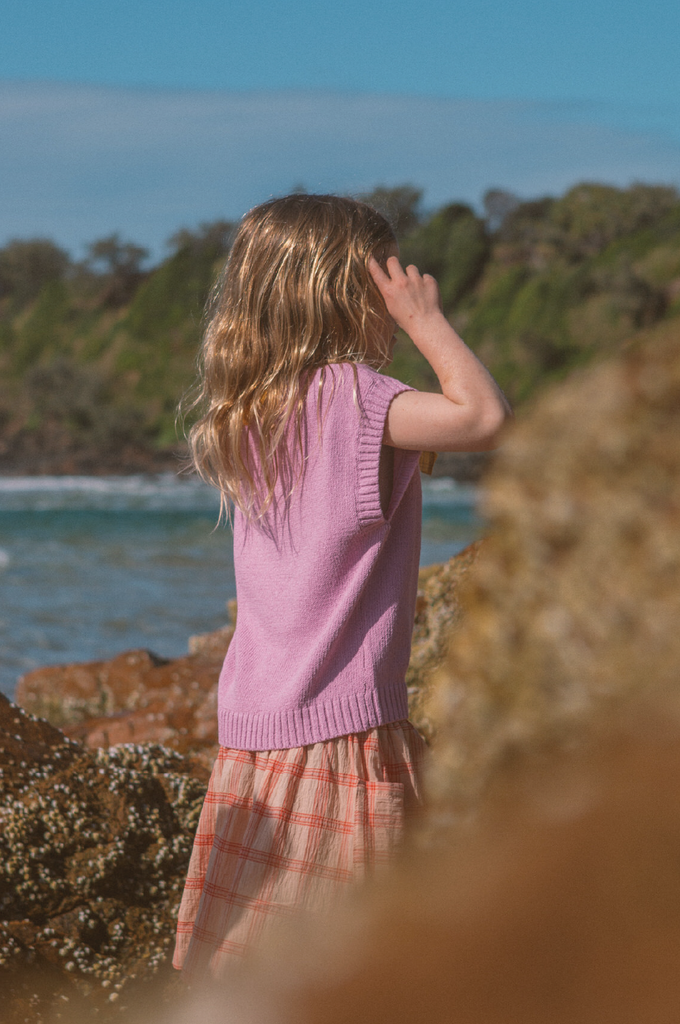 Young girl on the beach wearing a pink knit vest