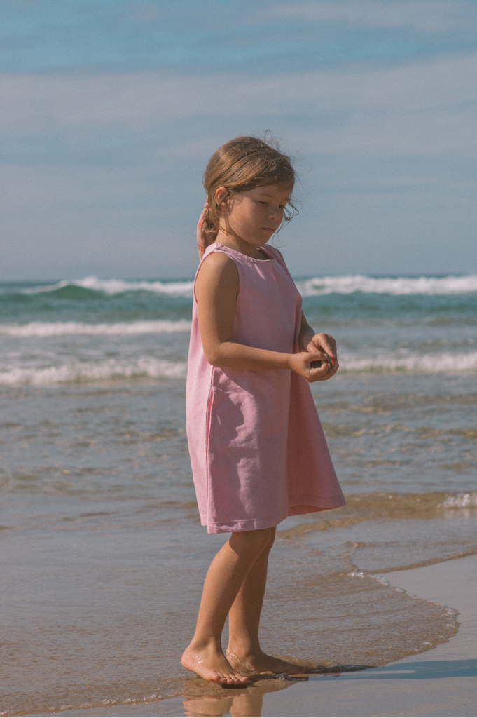 Young girl wearing a pink denim dress at the beach