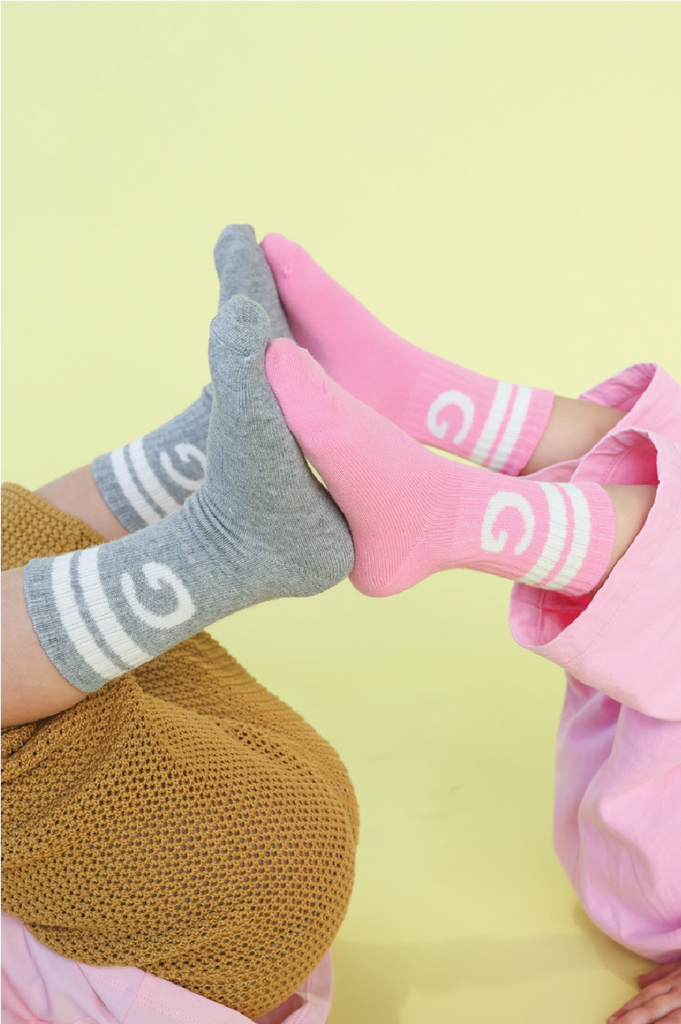 Grey and pink crew socks with white stripes on a yellow background