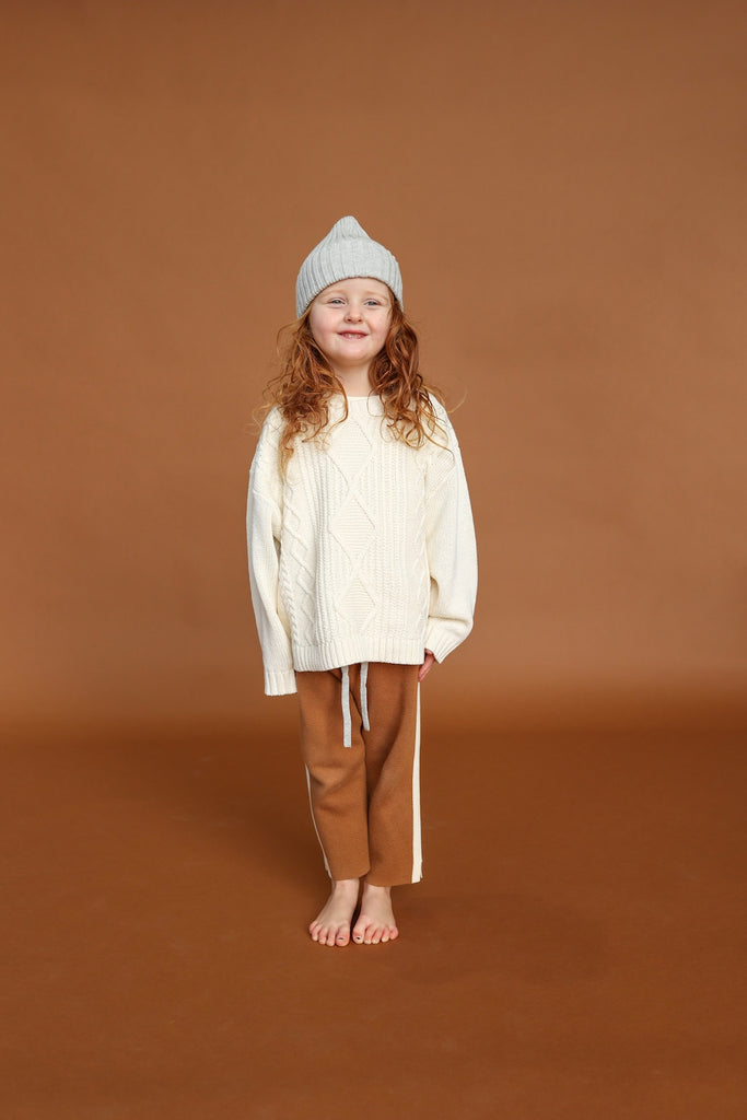 White milk sweater with cable knit pattern made from organic cotton for children with grey knitted beanie